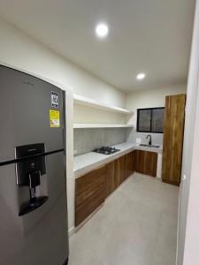 a kitchen with a stainless steel refrigerator and wooden cabinets at Cabaña santuarium cerca al mar in Tolú