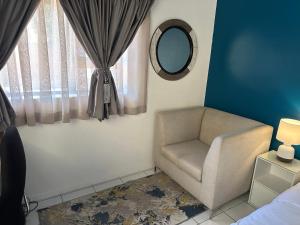a bedroom with a chair and a mirror at Private Cottage on Alamein in Cape Town
