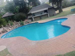 a large blue swimming pool with a house in the background at Silken Trap Budget Rooms in Johannesburg