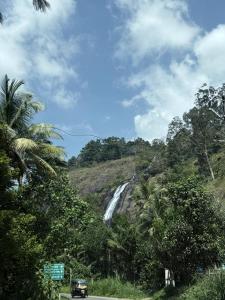 a car driving down a road next to a waterfall at Luxury Villa Ps5 Home-Theater Hookah 30km 2 Munnar in Chillithodu