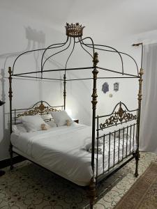 Casa Rural Huerto del Carmen في Puebla Larga: غرفة نوم مع سرير ذو مظلة معدنية مع ملاءات بيضاء
