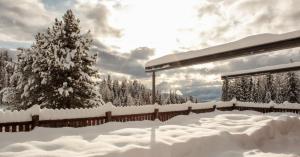a fence covered in snow with a tree in the background at Berghotel zum Zirm in Collalbo