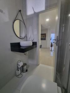 a bathroom with a sink and a mirror on the wall at Jequitibá Rosa - frente ao Mar na Praia de Meaípe, Guarapari in Guarapari