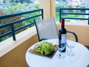 einen Tisch mit einer Flasche Wein und einem Teller Trauben in der Unterkunft Lycasti Maisonettes in Tavronítis