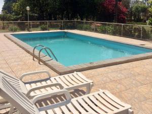a swimming pool with two lounge chairs next to it at Rancho Ouro Verde Rolândia Pr in Rolândia +15 photos