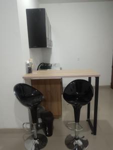 a desk with two black stools and a computer monitor at Económico práctico central in Cúcuta