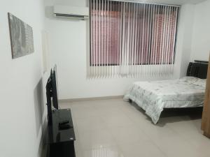 a white bedroom with a bed and a window at Económico práctico central in Cúcuta
