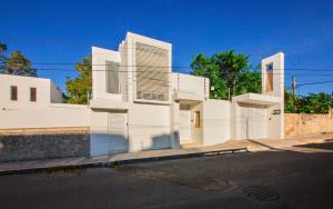 a white building with white shutters on a street at Casa CAMPANA, Privada, Piscina Privada, 3 Cuadras Malecón in Cozumel