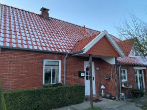 a red brick house with a red roof at Lüttje Huus Wirdum in Wirdum
