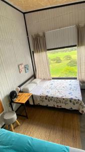 a bedroom with a bed and a table and a window at Cabaña2 con hermosa vista al valle in Oxapampa