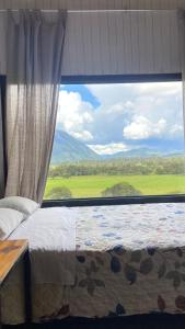 a bedroom with a large window with a view at Cabaña2 con hermosa vista al valle in Oxapampa