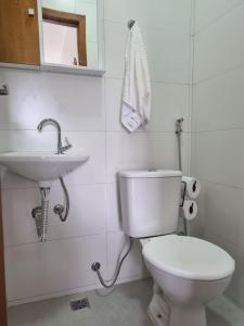 a bathroom with a white toilet and a sink at Jacarandá de Minas Vista Mar Praia de Meaipe Guarapari in Guarapari
