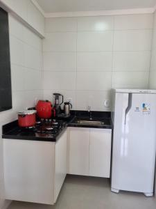 a kitchen with a stove and a white refrigerator at Jacarandá de Minas Vista Mar Praia de Meaipe Guarapari in Guarapari