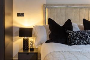 ブラッドフォードにあるBradford Luxury Central Apartmentのベッド(白黒の枕、ランプ付)