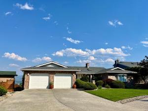 a house with two white garage doors in a driveway at Lake and the City Bed and Breakfast in West Kelowna