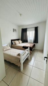 a bedroom with two beds and a window at Bembella casa em Balneario Camboriu in Balneário Camboriú