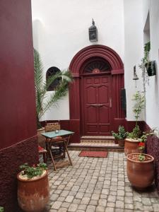 a red door in a building with potted plants at Riad Siham in El Jadida