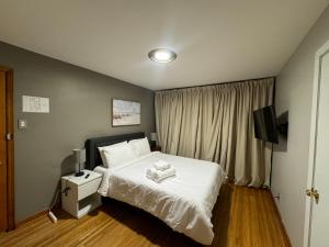 a bedroom with a white bed and a television at Charming Cape Cod Bungalow at Niagara Falls, NY! in Niagara Falls