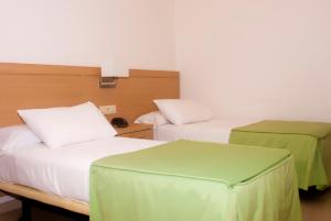 2 camas en una habitación con verde y blanco en Hotel El Duende, en Cambados
