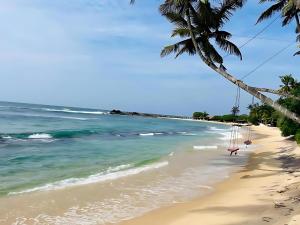 a beach with a swing hanging from a palm tree at Villa Minos in Hikkaduwa