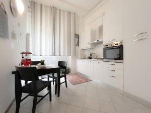 a white kitchen with a table and chairs and a refrigerator at Casa Vico Mandorla in Savona