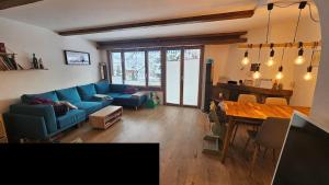 uma sala de estar com um sofá azul e uma mesa em Half chalet 2 min from ski bus em Laax