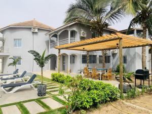 a house with a patio with chairs and a wooden umbrella at Villa Paco in Mbour