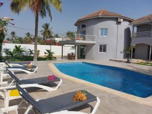 a swimming pool with lounge chairs and a house at Villa Paco in Mbour