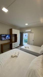 une chambre avec deux lits et une télévision au mur dans l'établissement Apartamento frente ao mar na praia do guaibim., à Guaibim 64 autres photos