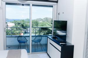 a bedroom with a view of a balcony with two chairs at Hotel Kaamú Taganga in Taganga
