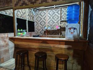 a bar with two stools and a drink cooler at Bua Guesthouse Tangkahan in Tangkahan
