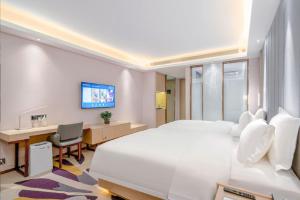una camera d'albergo con un grande letto bianco e una scrivania di Lavande Hotel Xi'an Xianyang International Airport Outlet a Xianyang