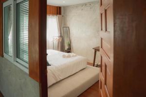 a bedroom with a white bed and a window at Baantonmai Farmstay in Ban Mai Ngae