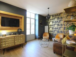 a living room with a couch and a tv at Appart rénové T2 bis, centre La Bourboule, WiFi, proche thermes - FR-1-608-277 in La Bourboule