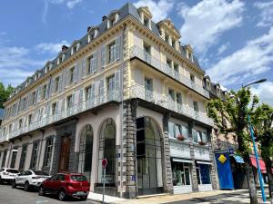 a building on a street with a red car parked in front at Appart rénové T2 bis, centre La Bourboule, WiFi, proche thermes - FR-1-608-277 in La Bourboule
