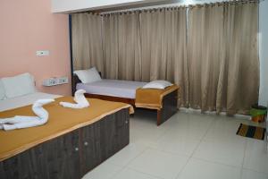 two beds in a room with two swans on them at ALAYA ROOMS in Tiruchchirāppalli +18 photos