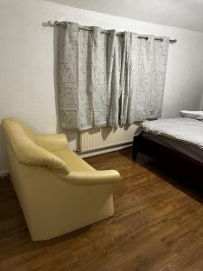 a bedroom with a chair and a bed and curtains at AT Apex House S in Dagenham
