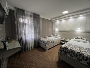 a hotel room with two beds and a desk at Status House in Fergana