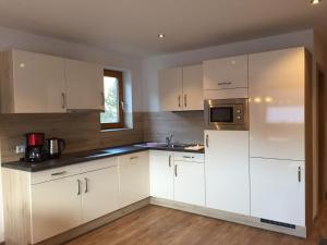 a kitchen with white cabinets and a microwave at Ferienwohnungen Bailom in Bach