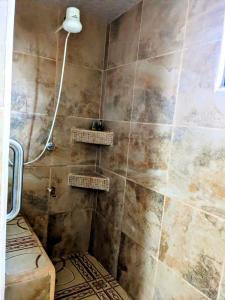 ein Badezimmer mit Dusche und gefliester Wand in der Unterkunft Garden Cottage in San Ignacio