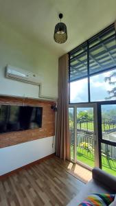 a living room with a large window and a flat screen tv at Blue Sky Monjam in Chiang Mai