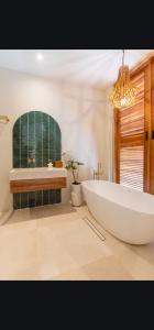 a large white tub in a bathroom with a window at Solid Surf Villa Mentawai in Tuapejat