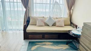 a couch with pillows on it in a room with windows at AYARU - APEC MANDALA Codotel SEA VIEW in Tuy Hoa