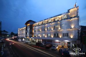 a large white building with cars parked in front of it at Kgees - Hill Town Hotel in Kattappana