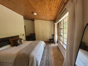 Un dormitorio con una cama grande con techo de madera. en Mid Century Modern Gem near town, en Stellenbosch
