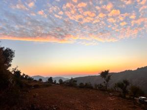 a sunset on a hill with a view of the mountains at The Tatwa Hotel & Camping in Chakrāta