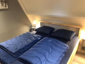 a bed with blue sheets and pillows on it at Bungalow for 12 guests on holiday park Vosseven in Stramproy