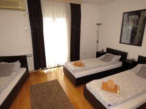 a room with three beds and a large window at Elite Guest House in Mostar