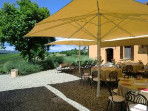 a restaurant with tables and chairs under a large yellow umbrella at Ca' Villa Club Agriturismo in Gabiano +20 photos