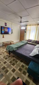 a bedroom with two beds and a tv on the wall at Mountain Breeze Homestay Meclo in Dharmsala +13 photos